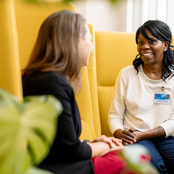 Image of a Mayo Clinic team member meeting with a woman on yellow chairs