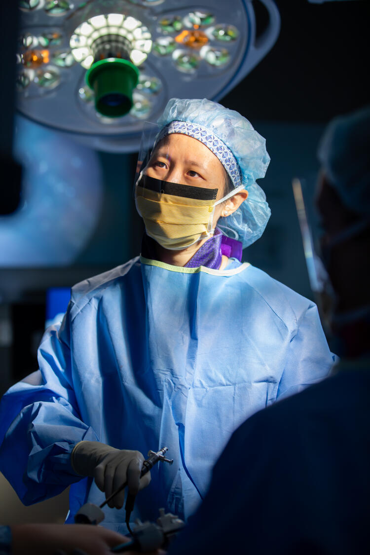 Surgeon using advanced instruments during an operation under bright surgical lights.